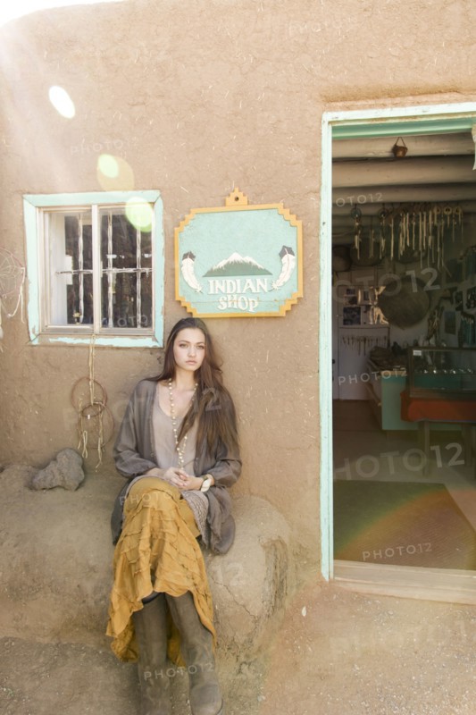 Hispanic teenage girl sitting near doorway to shop