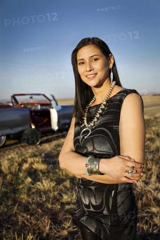 Portrait of smiling woman standing in grass near car