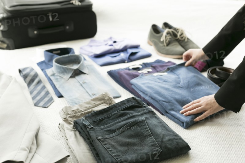 Hands of Caucasian woman arranging clothing for man on bed
