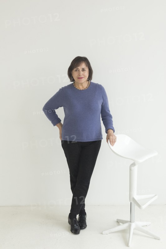 Confident older Mixed Race woman leaning on stool