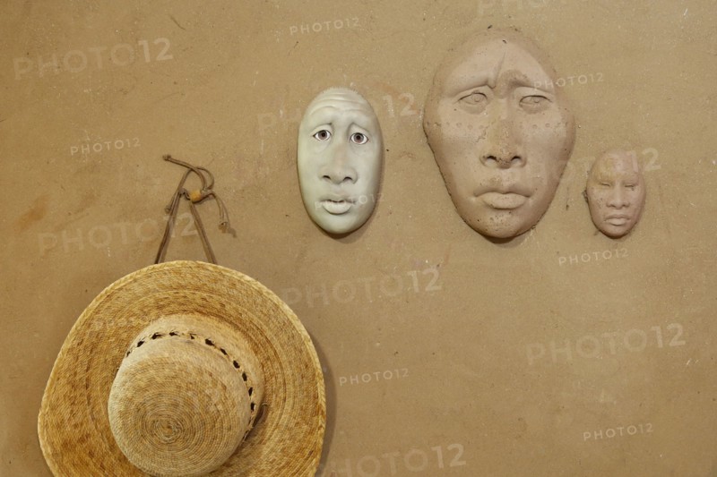 Clay masks and hat hanging on wall