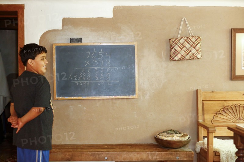 Proud Native American boy standing near equation on blackboard