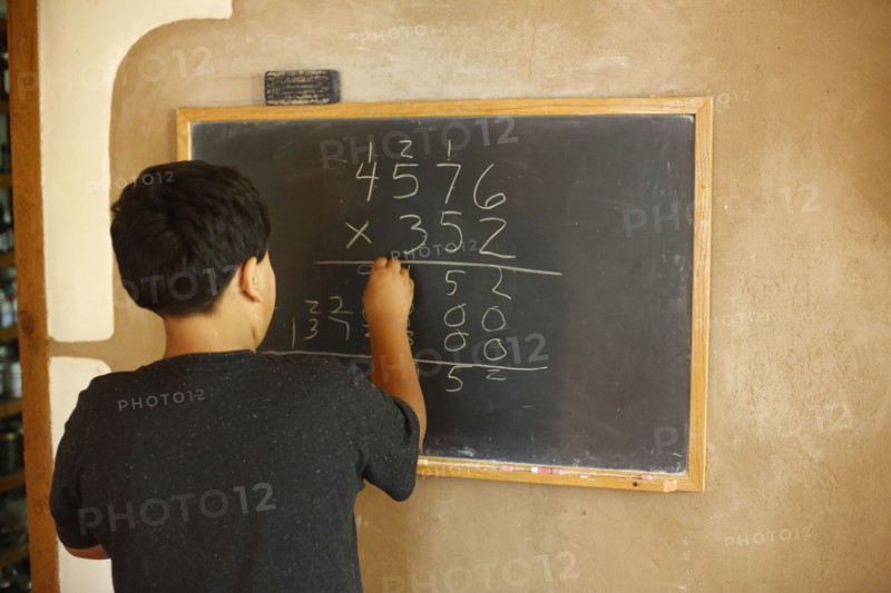 Native American boy solving equation on blackboard