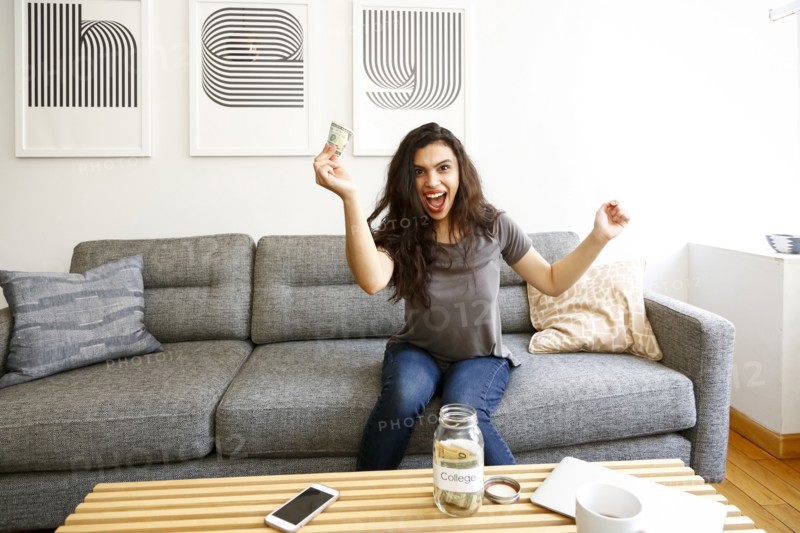 Mixed race woman celebrating with money for college