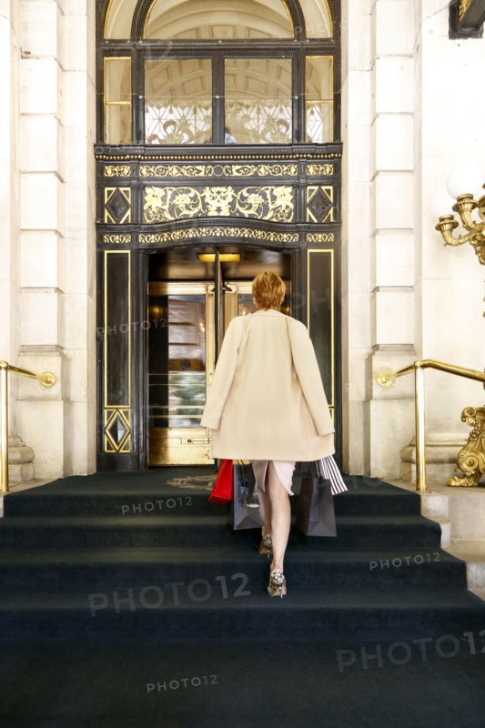 Glamorous Caucasian woman carrying shopping bags to luxury building