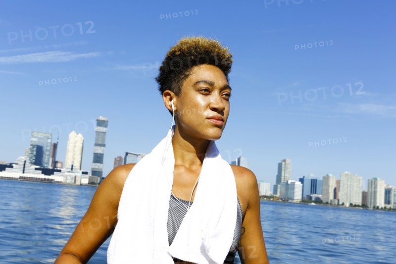 Mixed race woman listening to earbuds at waterfront