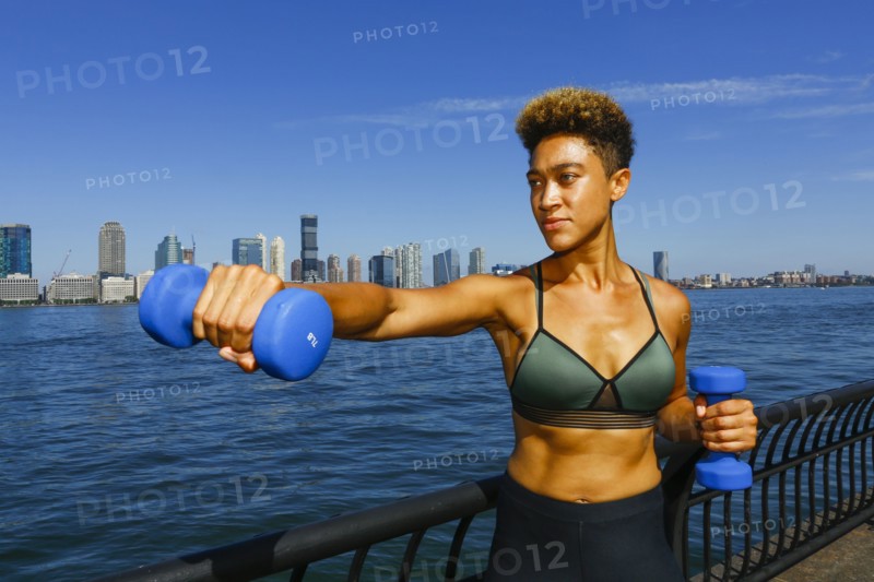 Mixed race woman lifting dumbbells at waterfront
