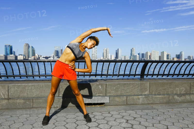 Mixed race woman stretching arm at waterfront
