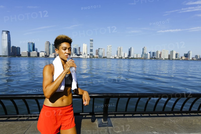 Mixed race woman drinking water from bottle at waterfront