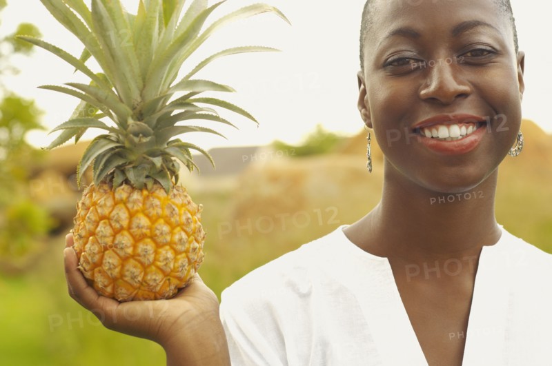 African American woman holding pineapple outdoors