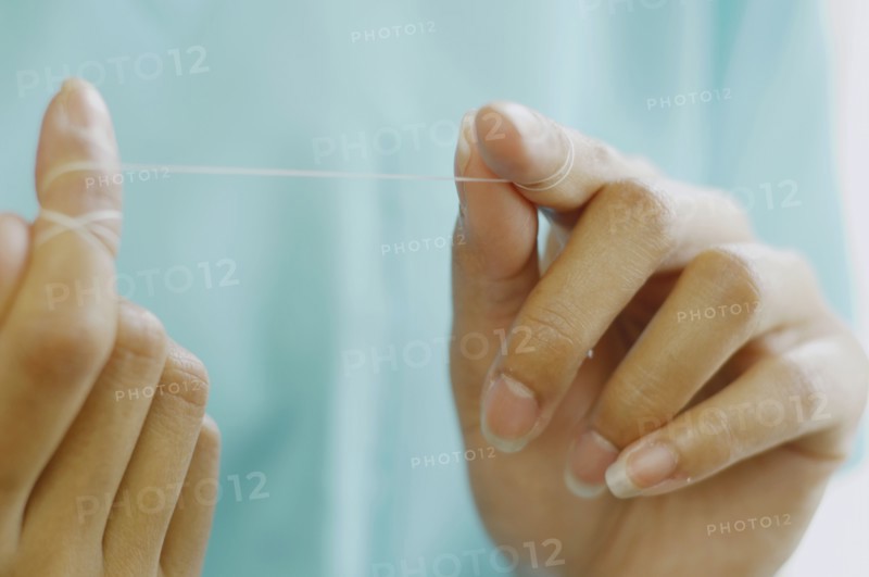 Close up of woman's hands with dental floss