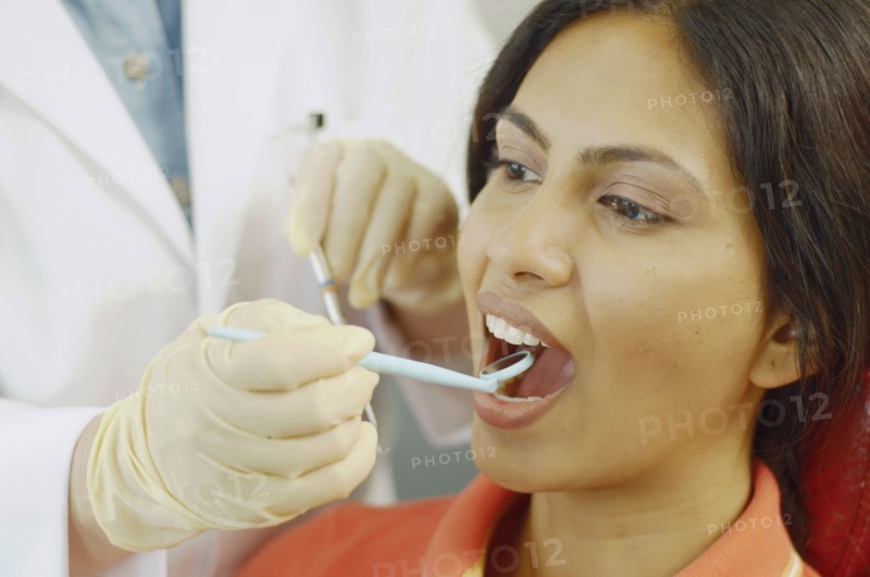 Dentist holding dental mirror in female patient's mouth