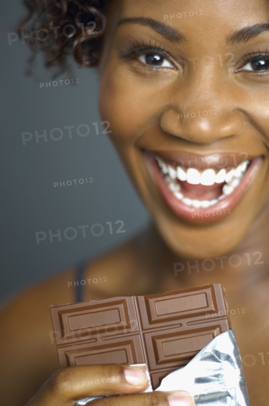 African woman eating chocolate bar