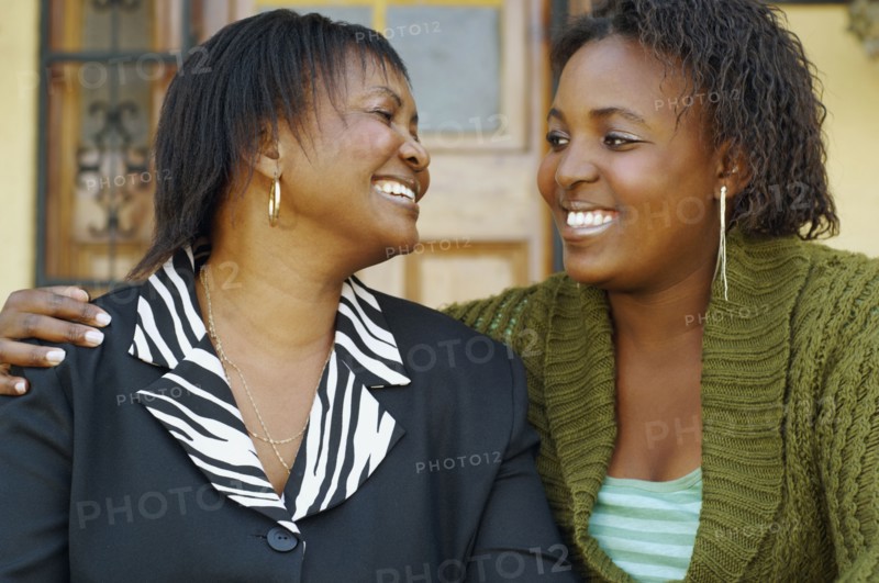 African mother and adult daughter smiling at each other