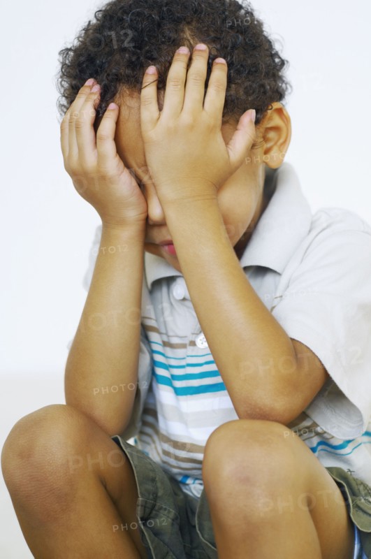 Mixed race boy with head in hands
