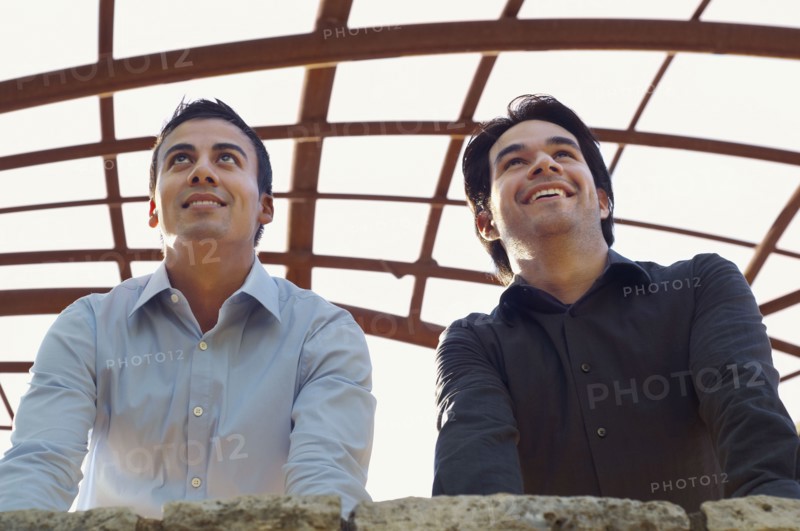 Hispanic businessmen leaning on wall