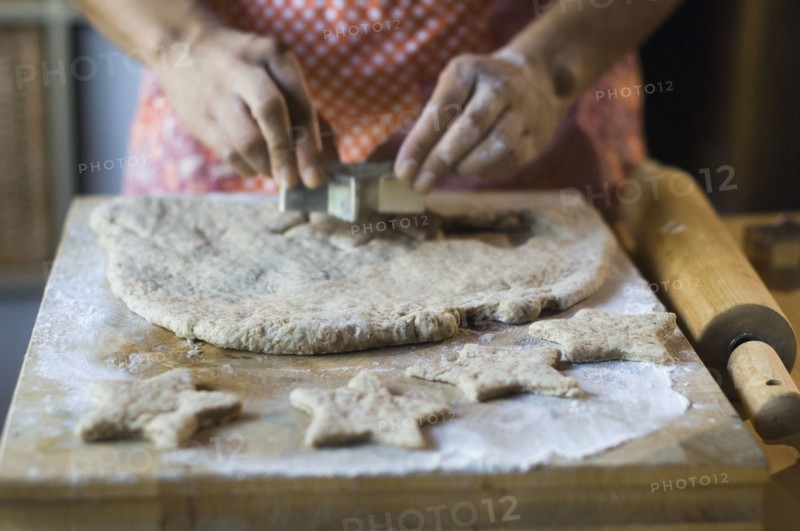 Mixed race woman cutting cookie dough in kitchen