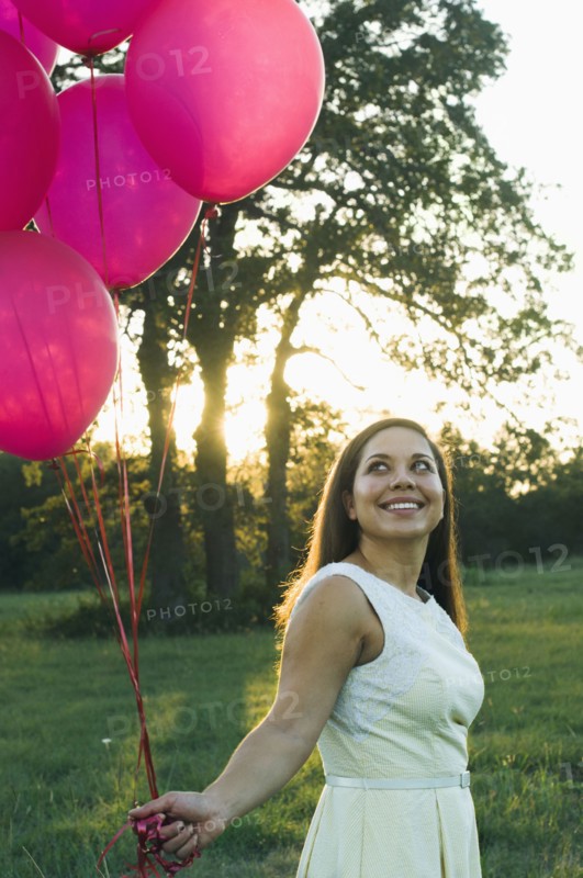 Mixed race woman with pink balloons in park