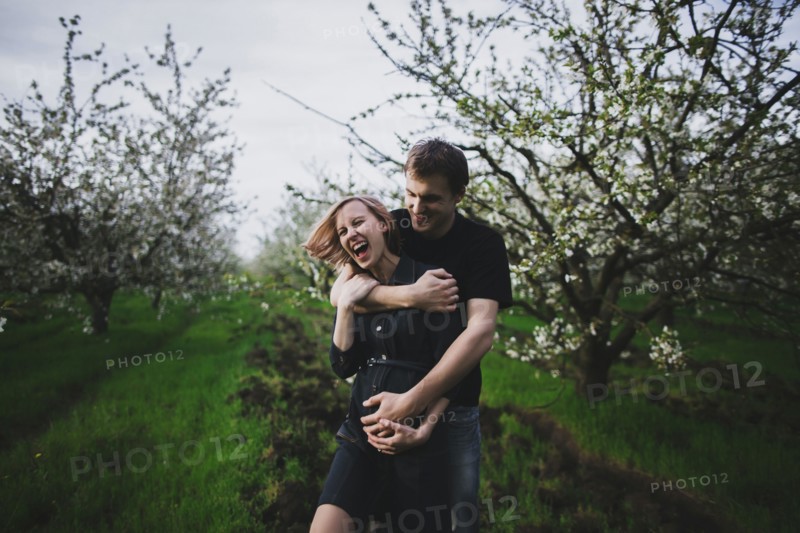 Caucasian couple hugging near trees