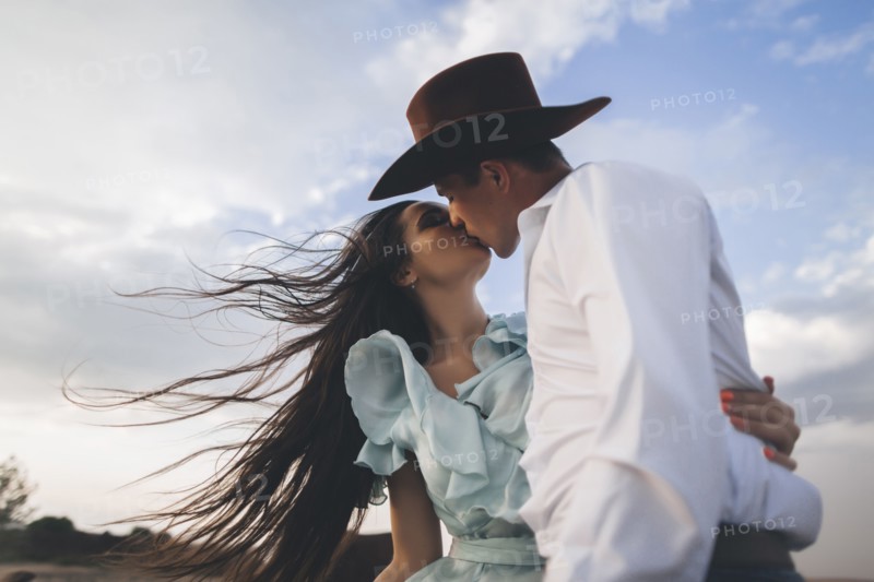Caucasian cowboy kissing woman in wind