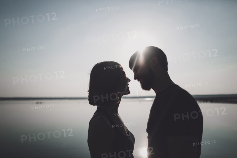Silhouette of smiling Caucasian couple at lake