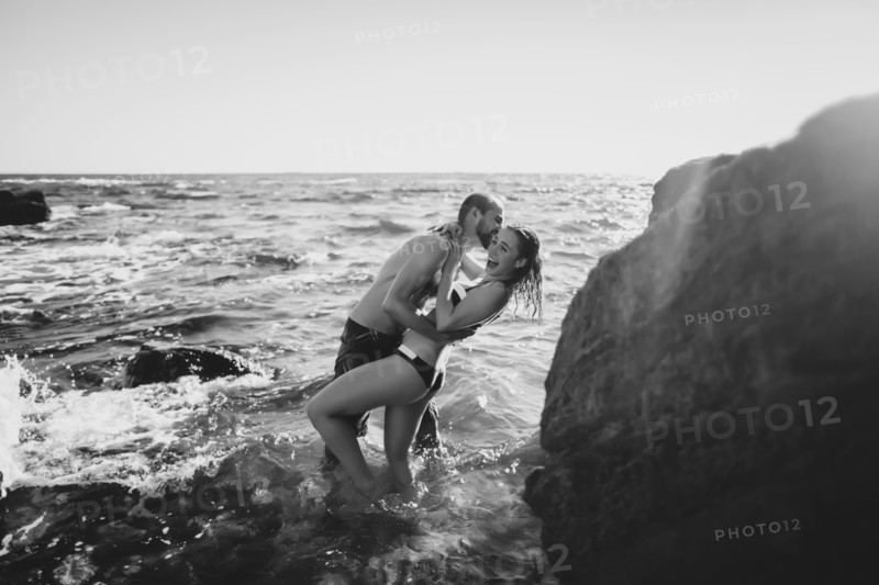 Caucasian couple laughing in ocean waves