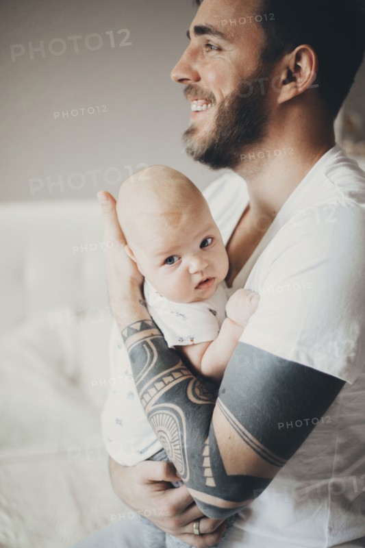 Caucasian father with tattoos on arms holding baby son