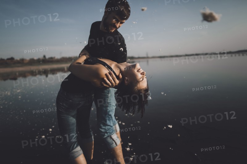 Caucasian man dipping woman at lake