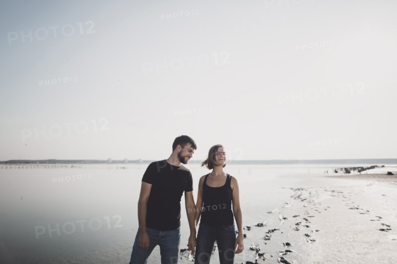 Caucasian couple holding hands on beach