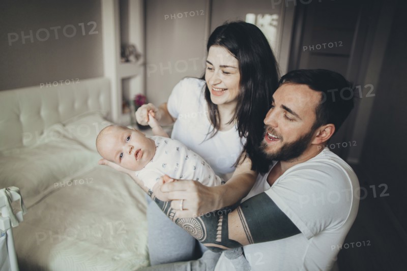 Caucasian mother and father on bed playing with baby son