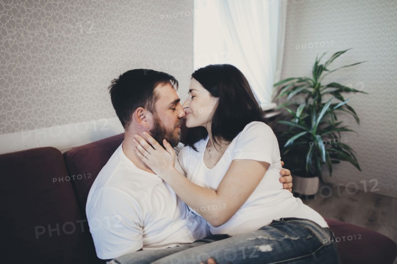 Caucasian couple cuddling and kissing on sofa