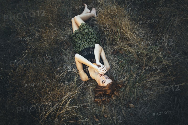 Pensive Caucasian woman laying on grass