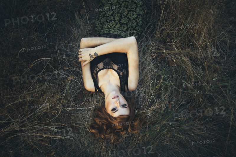 Serious Caucasian woman laying on grass