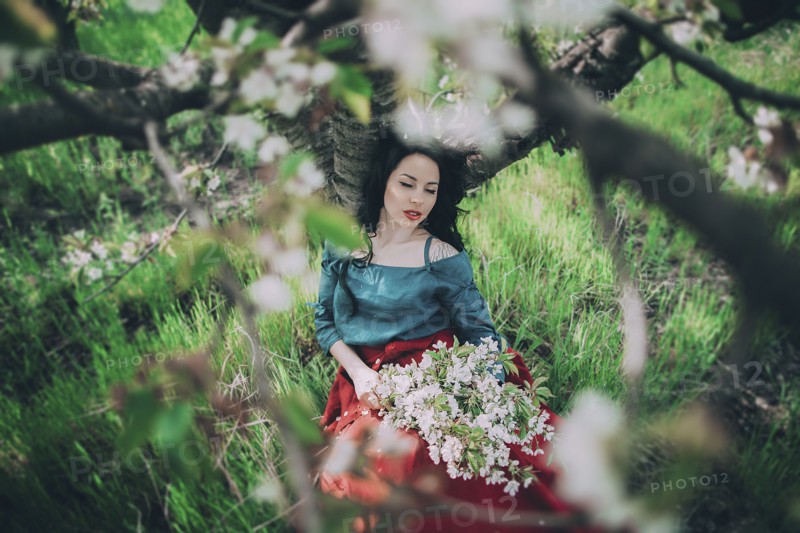 Caucasian woman leaning on tree holding flowers