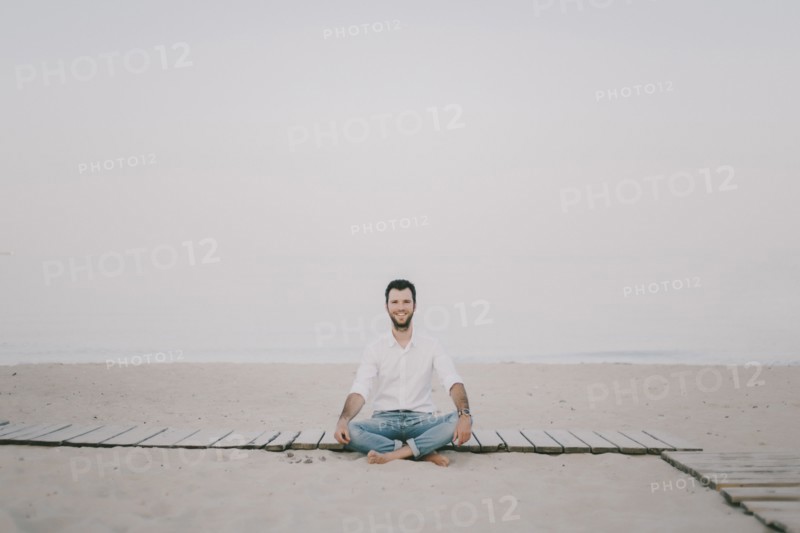 Caucasian man sitting on boardwalk at beach