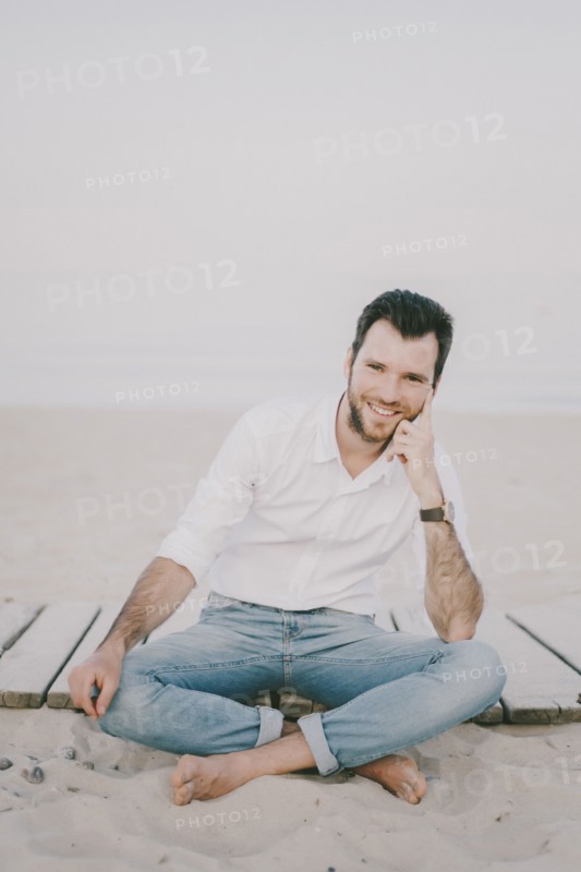 Caucasian man sitting on boardwalk at beach
