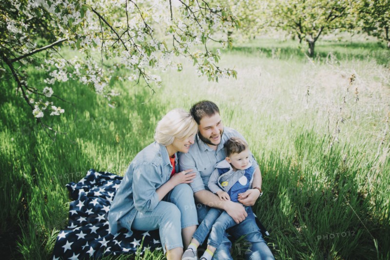 Caucasian multi-generation family sitting on blanket in grass