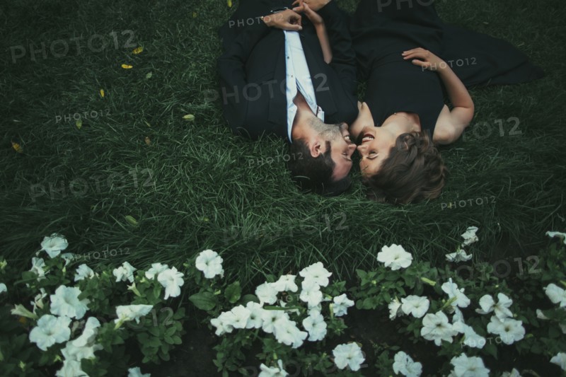Caucasian couple laying in grass laughing