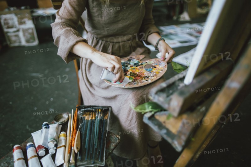 Caucasian woman squeezing paint onto palette