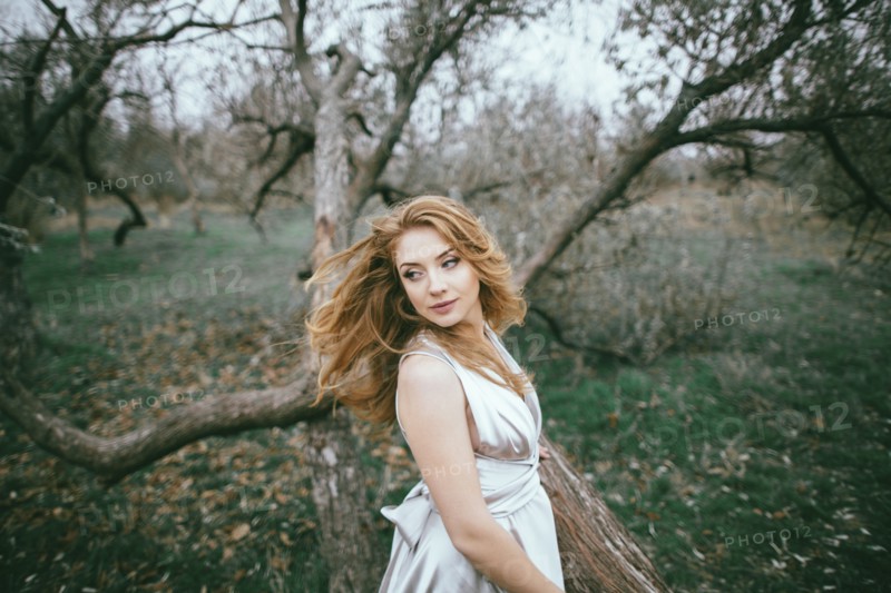 Glamorous Caucasian woman tossing hair near tree