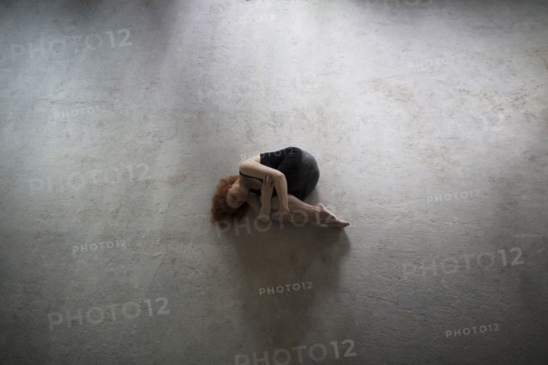 Caucasian woman laying on concrete in fetal position