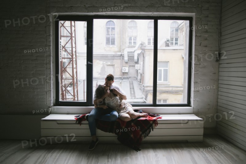 Caucasian couple kissing on bench near window