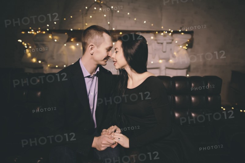 Caucasian couple sitting on sofa rubbing noses