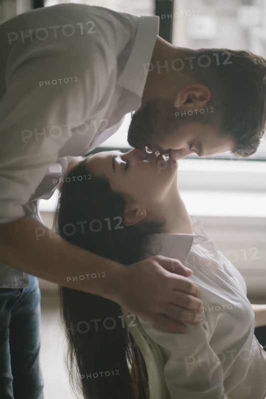 Caucasian man kissing woman in chair