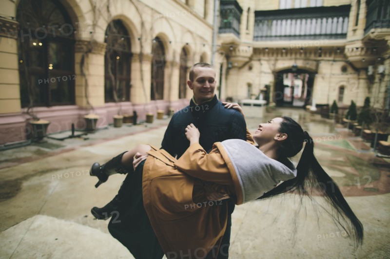 Caucasian man lifting and carrying woman in courtyard