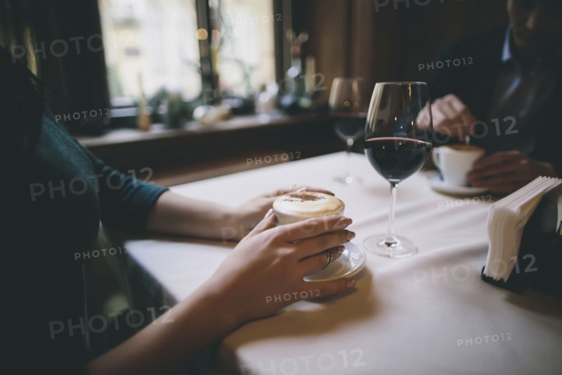 Hands of Caucasian couple drinking coffee and wine