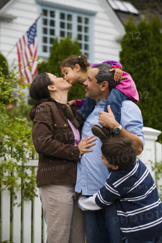 Mother kissing daughter while family watches