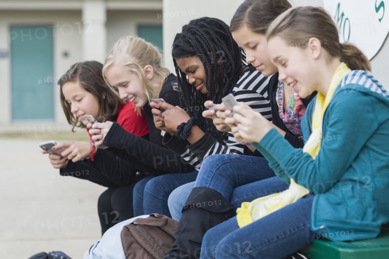 School girls text messaging on cell phones