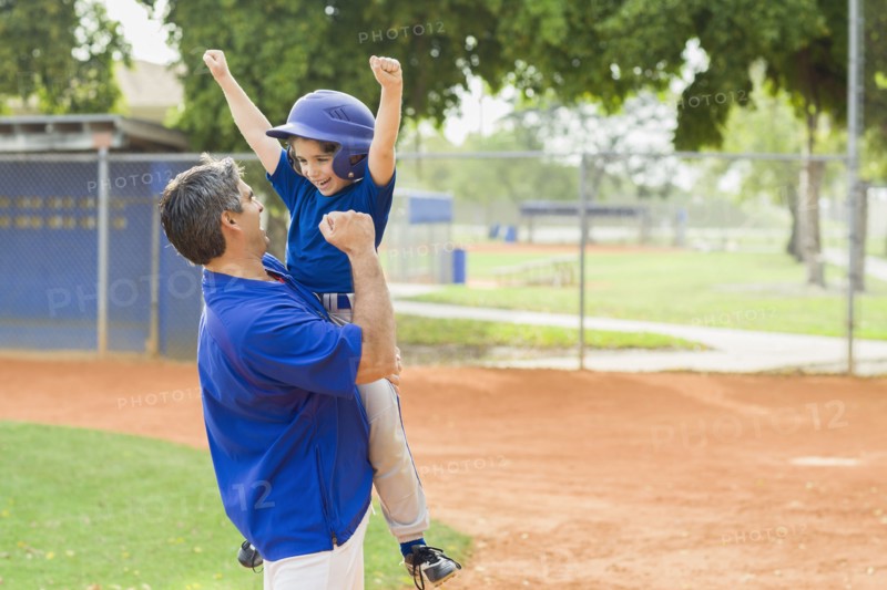 Hispanic coach and young baseball player cheering