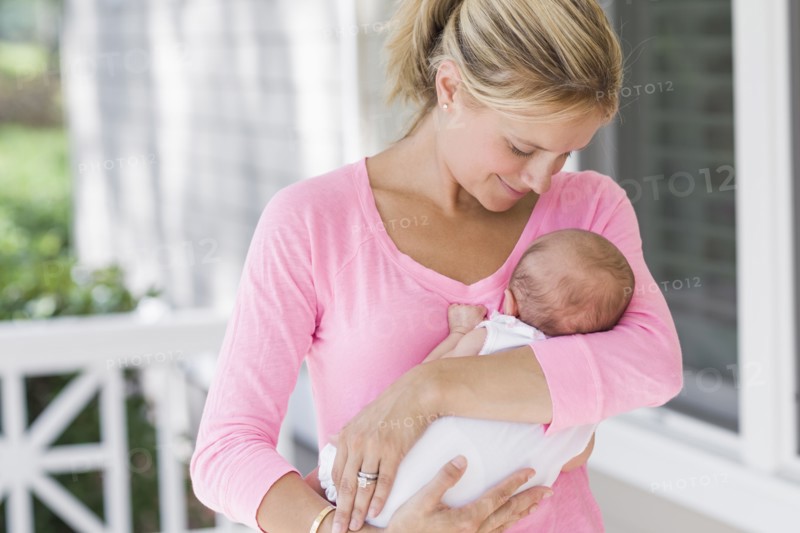 Caucasian mother holding baby on porch